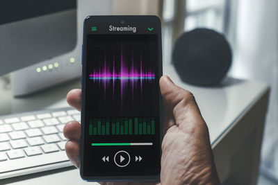 Smartphone in hand playing music. radio broadcast audio and sharing sound streaming concept.