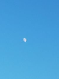Low angle view of moon against clear blue sky