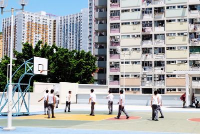 Boys playing basketball against buildings in city