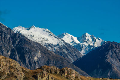 Scenic view of snowcapped mountains against clear blue sky