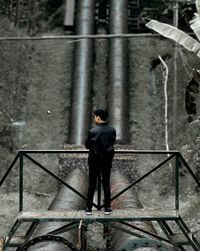 Rear view of man standing on railing