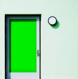 Close-up of green door and window on white wall