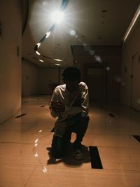 Full length of man sitting on floor in illuminated building