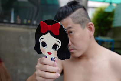 Close-up portrait of shirtless man holding camera