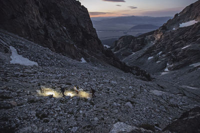 Three hikers walk at dawn through a vast glacier rock field, wyoming