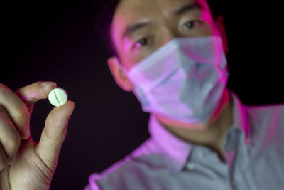 Close-up portrait of man holding cigarette over black background