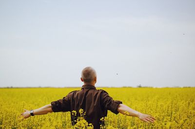 Rear view of man on field against clear sky