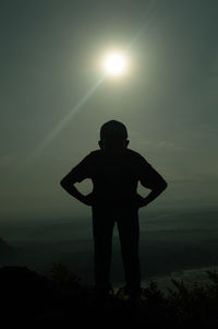 Rear view of a silhouette boy standing against sky