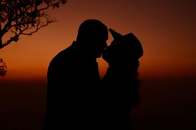 Silhouette couple against orange sky during sunset