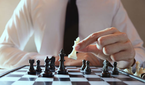 Midsection of businessman playing chess in office