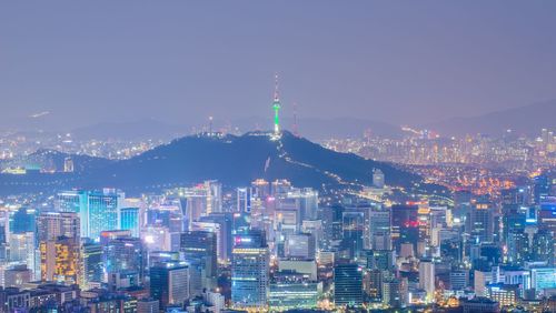 Illuminated buildings in city against sky at night