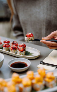 Eating sushi with chopsticks close up, food takeout and delivery service, salmon sushi rolls.