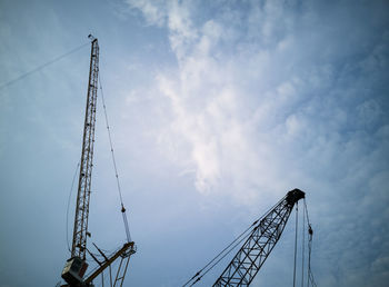 Low angle view of cranes against sky