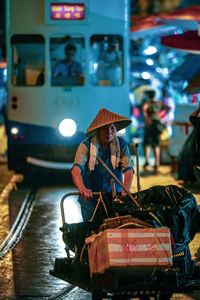 Man holding umbrella while sitting in bus at night