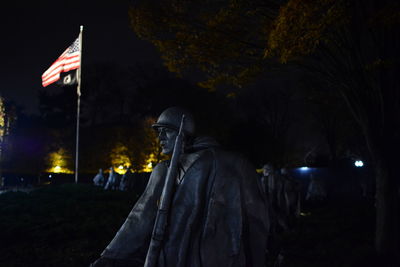 Statue amidst trees against sky at night