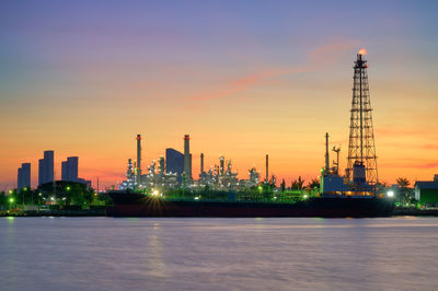 Illuminated factory against sky during sunset