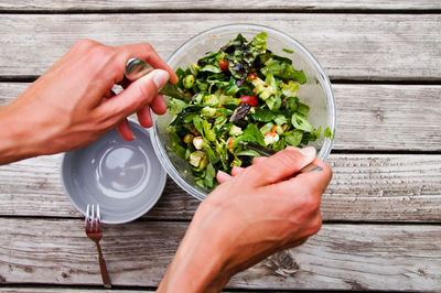 Cropped hands making salad