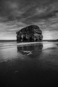 Rock formation on beach against sky