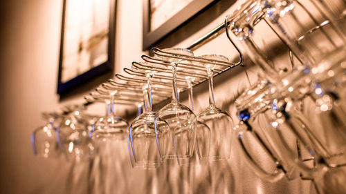 Close-up of wineglasses hanging from rack in bar