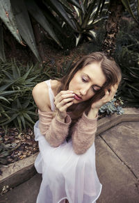 Young woman sitting against succulent plants