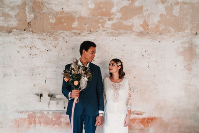 Young couple standing against wall