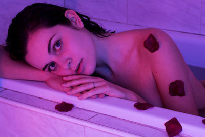 Portrait of naked woman in bathtub with rose petals at home