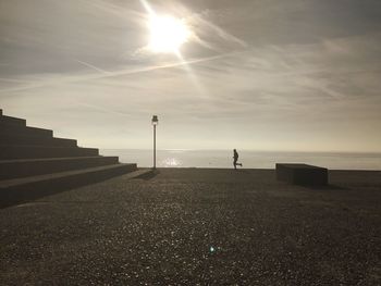 Silhouette man running at promenade against sky