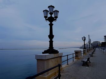 Street light by sea against sky