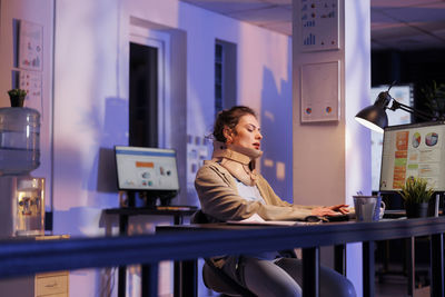 Side view of woman using mobile phone while sitting in cafe