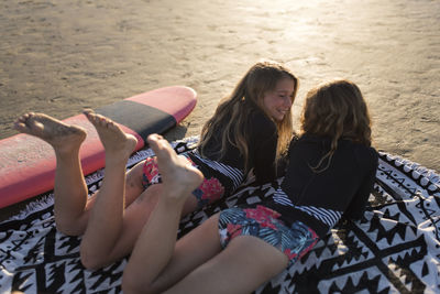 Twin sisters laughing while lying on the beach