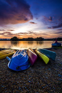 Multi colored boats moored on beach against sky during sunset