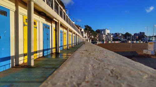 Footpath amidst buildings against blue sky
