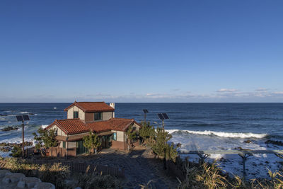 Buildings by sea against clear blue sky