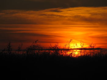 Silhouette landscape against dramatic sky during sunset