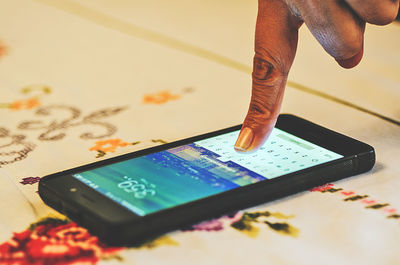 Close-up of hand using smart phone on table