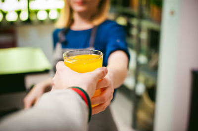 Cropped hand of man taking drink from woman at home