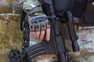 Midsection of military man holding rifle