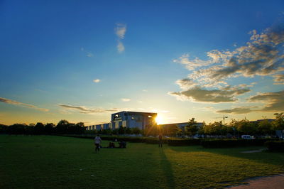 People on soccer field against sky during sunset