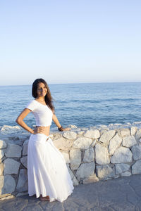 Full length of woman standing by sea against clear sky