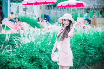 Portrait of young woman standing against plants