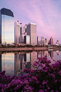 City by river and buildings against sky