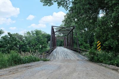 Footbridge against cloudy sky