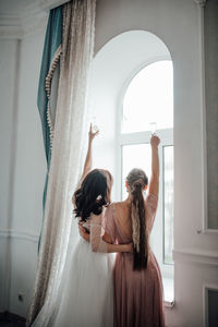 Rear view of woman standing by window