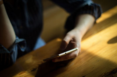 Close-up of man using mobile phone on table