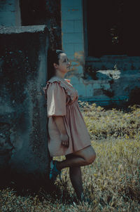 Woman looking away while standing against wall