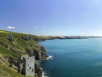 Scenic view of rocky coastline against blue sky