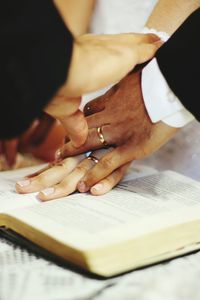 Midsection of couple with priest touching bible in church