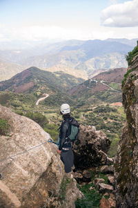Concept: adventure. climbers man with helmet and harness. from behind looking at the andalusian natural landscape. climbing to the top of the mountain. via ferrata on rock.