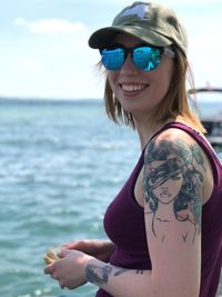 Portrait of smiling woman wearing sunglasses at sea shore