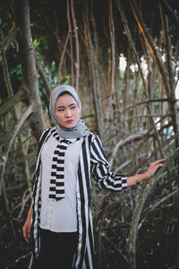 Portrait of young woman standing in forest